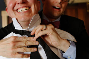 Groomsman helps groom with his tie