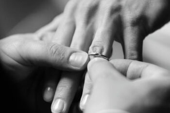 groom puts ring on brides finger