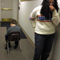 Tanesha Dixon giggles at Cory while his sits in “silence and stillness” in the hall at his after school program. Cory uses his silence and stillness time, similar to a time out, to relax and recollect his thoughts in transition times and when he cannot behave appropriately with the group.