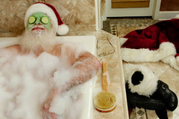 Self-care is important during the holidays. santa claus with a facial mask in a bath tub