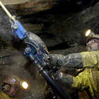 Ron Head, left, and Kevin Clark bolt down a mat on the ceiling of the mine. Bolts and mats increase the stability of the mine and help prevent cave-ins.
